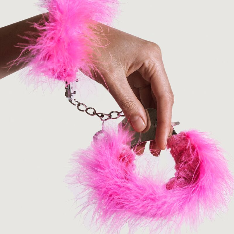 Close-up das algemas Adrien Lastic de metal com penas rosa para BDSM e bondage.