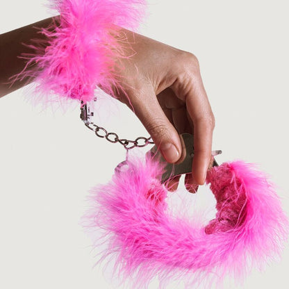 Close-up das algemas Adrien Lastic de metal com penas rosa para BDSM e bondage.